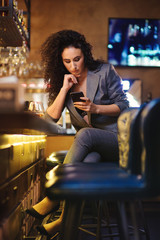 Elegant lady in a business suit, in a restaurant at a bar counter alone