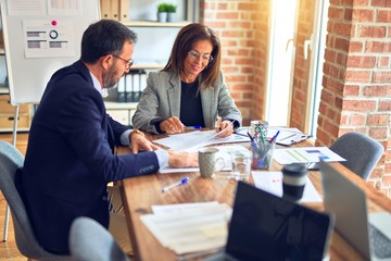 Two middle age business workers smiling happy and confident. Working together with smile on face at the office