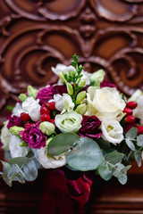 Vertical image of beautiful, stylish wedding bouquet of red, pink roses and eucalyptus greenery on wooden background. Summer floral composition.