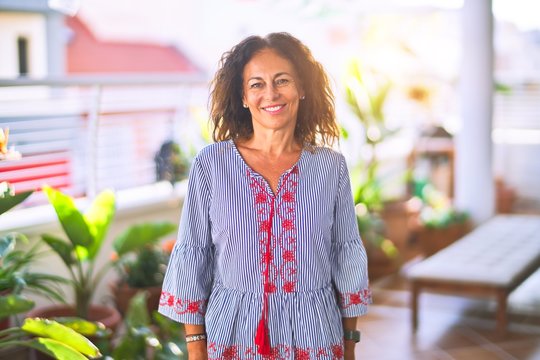 Middle age beautiful woman smiling happy and confident standing with a smile on face at terrace
