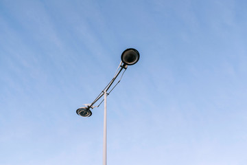 A modern city street lamp in the center of the photograph with the blue sky clear in the background