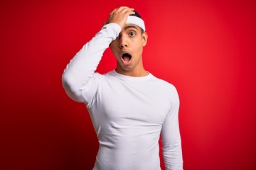 Young handsome african american sportsman wearing sportswear over red background surprised with...