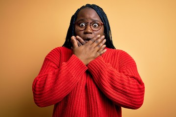 Obraz premium African american plus size woman with braids wearing casual sweater over yellow background shocked covering mouth with hands for mistake. Secret concept.