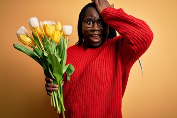 Young african american plus size woman with braids holding bouquet of yellow tulips flower...