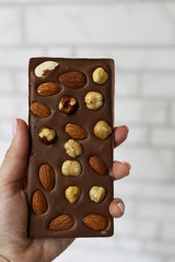 Hand holds dark natural handmade dark chocolate