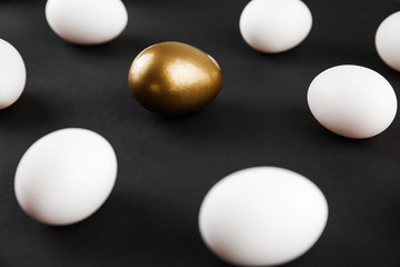 Fototapeta na wymiar White and gols eggs arranged on black background