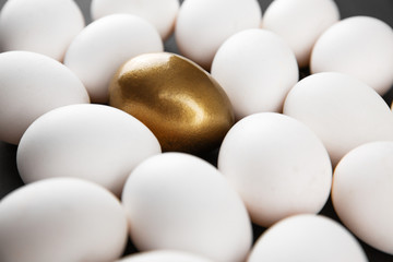 White and gols eggs arranged on black background