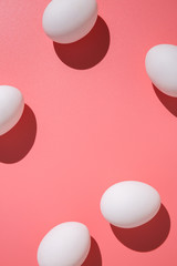 Casual arrangement of white chicken eggs on pink chicken table flat lay.