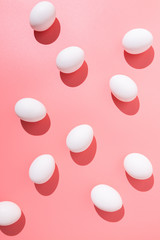 Casual arrangement of white chicken eggs on pink chicken table flat lay.