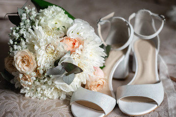 Horizontal image of modern a beautiful, stylish wedding bouquet of white, yellow roses, female shoes and eucalyptus greenery. Summer floral composition.