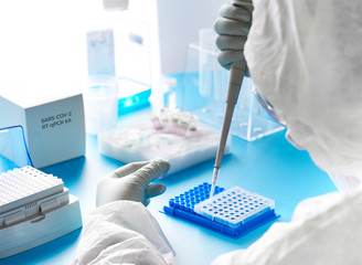 SARS-COV-2 pcr diagnostics kit. Epidemiologist in protective suit, mask and glasses works with...