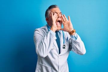 Middle age handsome grey-haired doctor man wearing coat and blue stethoscope Shouting angry out loud with hands over mouth