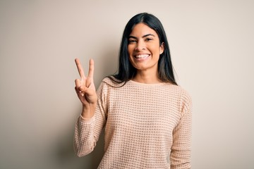 Young beautiful hispanic woman wearing elegant pink sweater over isolated background showing and...