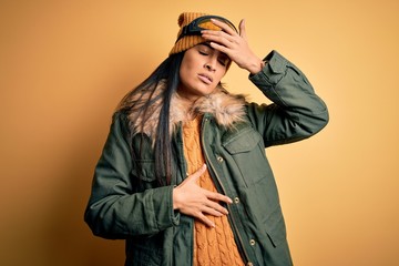 Young beautiful hispanic woman wearing ski glasses and coat for winter weather Touching forehead for illness and fever, flu and cold, virus sick
