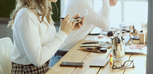 make up artist doing professional make up of young woman