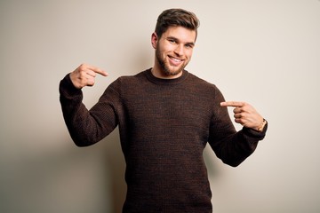 Fototapeta premium Young handsome blond man with beard and blue eyes wearing casual sweater standing looking confident with smile on face, pointing oneself with fingers proud and happy.