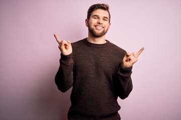 Young blond man with beard and blue eyes wearing casual sweater over pink background smiling...