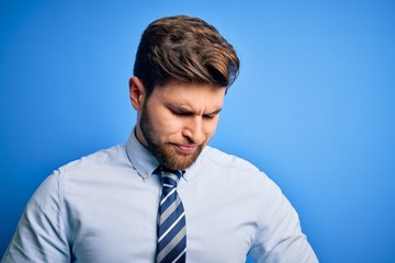 Young blond businessman with beard and blue eyes wearing elegant shirt and tie standing with hand on stomach because indigestion, painful illness feeling unwell. Ache concept.