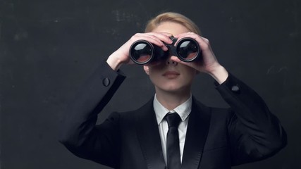 businesswoman in a classic business suit and binoculars - Powered by Adobe