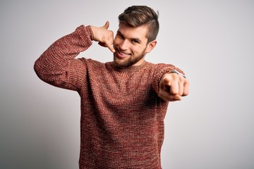 Young blond man with beard and blue eyes wearing casual sweater over white background smiling doing...