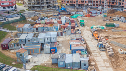 Fototapeta premium Aerial view of change houses for workers at construcrion area with concrete and construction materials around on gloomy day. Accomodation types and color accents concept.