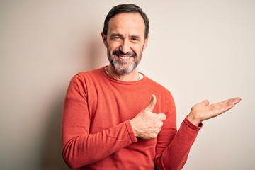 Middle age hoary man wearing casual orange sweater standing over isolated white background Showing palm hand and doing ok gesture with thumbs up, smiling happy and cheerful