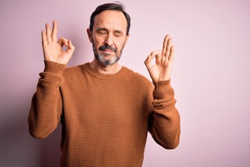 Middle age hoary man wearing casual brown sweater standing over isolated pink background relax and smiling with eyes closed doing meditation gesture with fingers. Yoga concept.