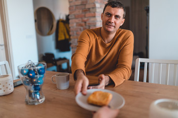 Couple in the kitchen eat breakfast with orange juice and pastry at table