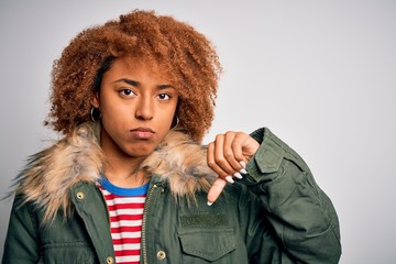 Young beautiful African American afro woman with curly hair wearing casual winter coat with angry...