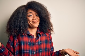 Young beautiful african american woman wearing casual shirt over isolated background clueless and confused expression with arms and hands raised. Doubt concept.