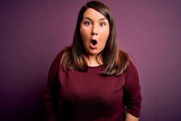 Fototapeta premium Beautiful brunette plus size woman wearing casual sweater over isolated purple background afraid and shocked with surprise expression, fear and excited face.