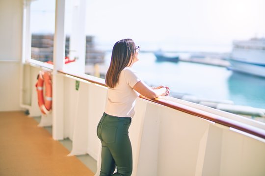 Young beautiful woman on vacation smiling happy and confident. Standing on a deck of ship with smile on face doing a cruise