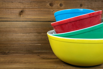 stack of retro colorful mixing bowls on rustic wood