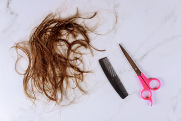 Cropped view of long brown female hair scissors and comb