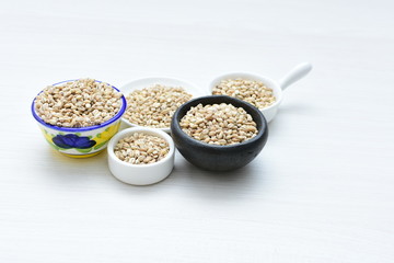 Raw barley grains, displayed in containers on textured background