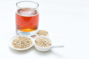 Raw barley grains, released in containers and accompanied by a glass of beer
