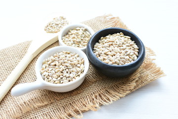 Raw barley grains, displayed in containers on textured background
