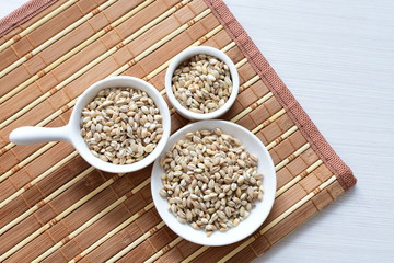 Raw barley grains, displayed in containers on textured background