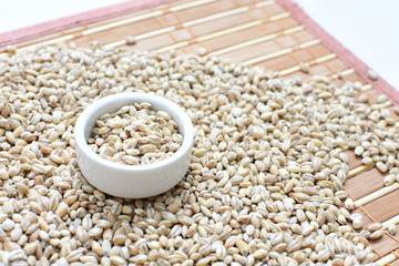 Raw barley grains, displayed in containers on textured background