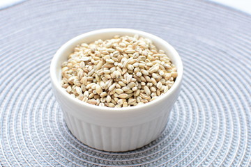 Raw barley grains, displayed in containers on textured background