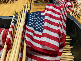a stack of mini American Flags are stacked as they are prepared to be placed at the National Cemetery