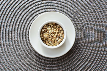 Raw barley grains, displayed in containers on textured background