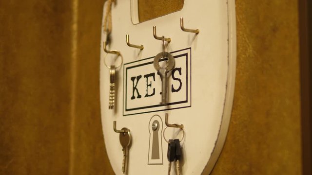 Person hanging House Keys on a hook key holder on the wall. 