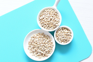 Raw barley grains, displayed in containers on textured background