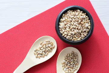 Raw barley grains, displayed in containers on textured background