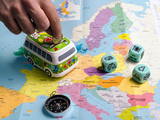 map of europe, caravan shaped piggy bank, compass and activity dice - concept of saving and planning for travel