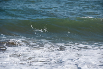 Mediterranean sea at sunset. Waves break on the sandy shore, sea foam. Natural background
