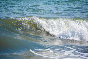 Mediterranean sea at sunset. Waves break on the sandy shore, sea foam. Natural background