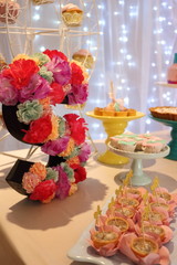 Party table, candies, homemade dessert, lovely details. Front view. Bokeh lights background. Letter S made by flowers decoration