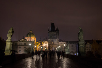 Old town bridge tower of Charles Bridge (Karluv Most), or staromestska mostecka vez in Prague, Czech Republic, at night, with the shapes of tourists walking on it
